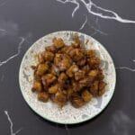 A marble counter features a plate of fried chicken, enhanced with SpicyMama Mammy Sauce for a spicy kick.