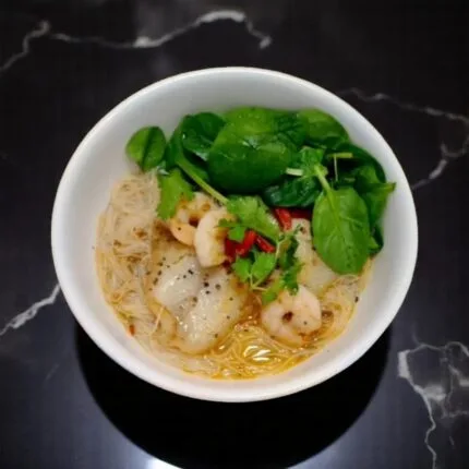 A bowl filled with beenhoon prawn and vegtables and spicymama anchovy soup