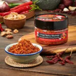 A bowl of spicymama crispy spicy shrimp and a bottle of the crispy spicy shrimp, showcasing vibrant red spices for culinary use.