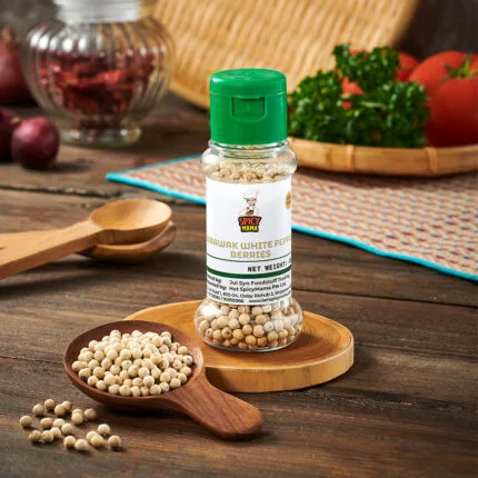 A bottle of Sarawak White Pepper Berries placed on a wooden board, showcasing a rustic kitchen setting.