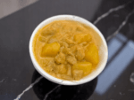 A hearty bowl of curry with chunks of meat and potatoes displayed on a dining table.