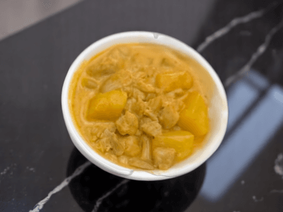A hearty bowl of curry with chunks of meat and potatoes displayed on a dining table.
