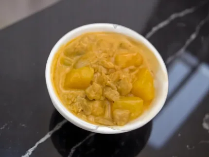 A hearty bowl of curry with chunks of meat and potatoes displayed on a dining table.