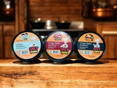  Three jars of Spicymama Anchovy with varying spiciness levels displayed on a wooden counter.