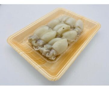 A clear plastic tray with several fresh, small, white squids arranged neatly, set on a light wooden surface. from s.s kim