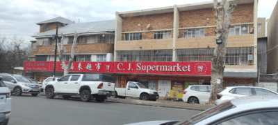  C.J. Supermarket in South Africa with cars parked outside, displaying a sign that says "Chinese Supermarket."