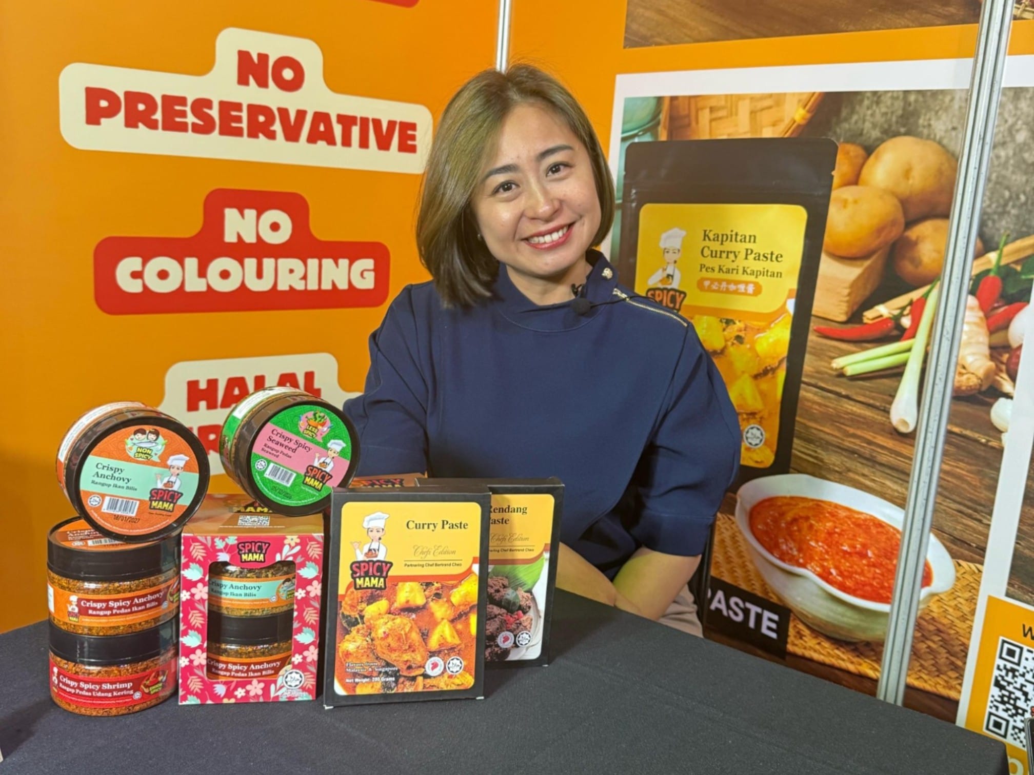 SpicyMama Brings South East Asian Flavors to South Africa at the 2025 Brands Road Show 1 A woman seated at a table surrounded by an assortment of food products, showcasing a variety of colors and textures. at south africa