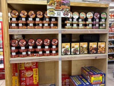 A shelf in C.J. Supermarket, South Africa, featuring an assortment of SpicyMama condiments and diverse food products.