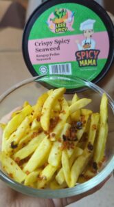 A person presents a bowl of crispy fries accompanied by a small container of Spicymama crispy seaweed