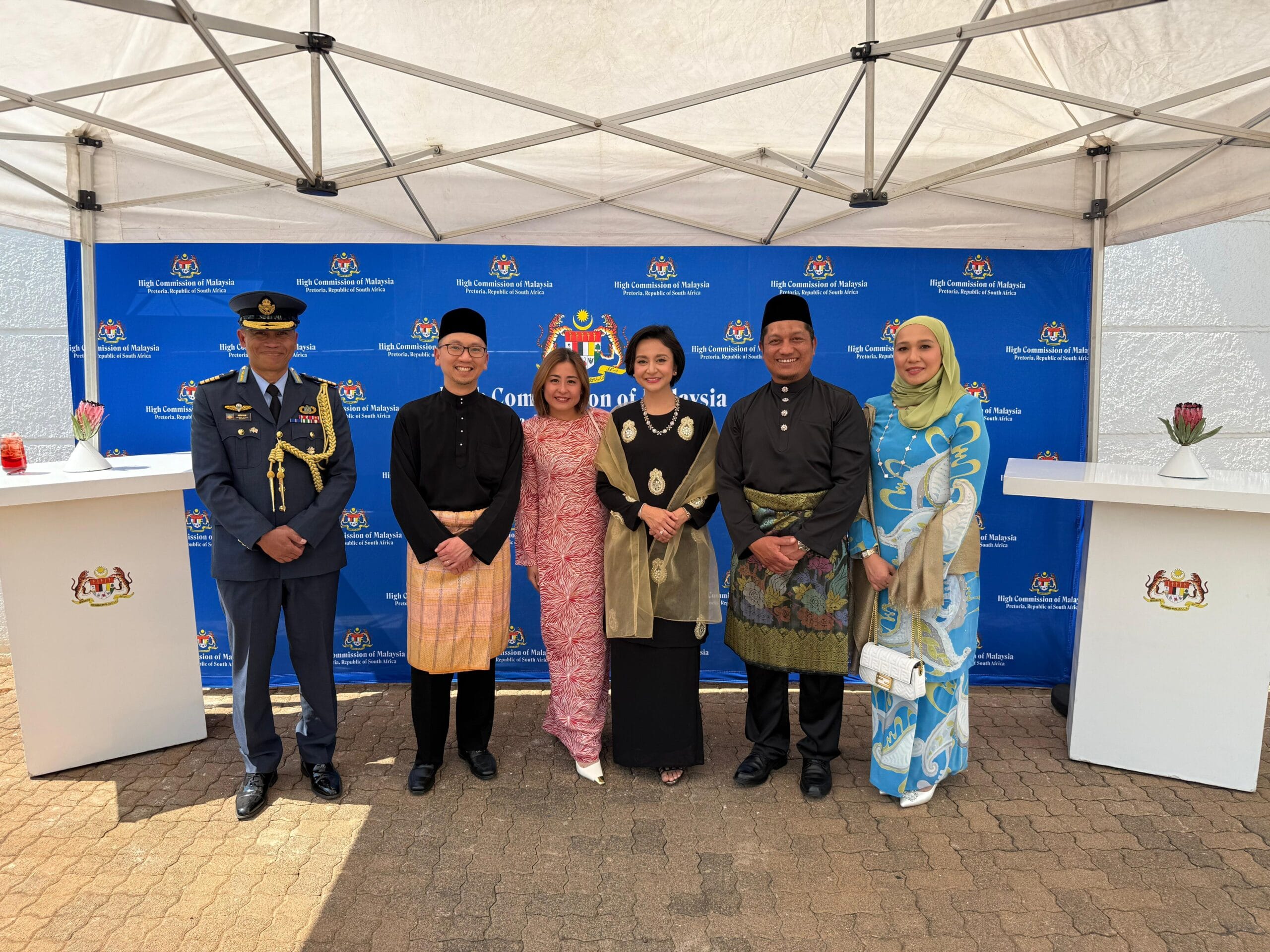 SpicyMama's Memorable Catering Experience at Malaysian Embassy in South Africa 1 A group of people of various ages and backgrounds standing under a tent, participating in a social event outdoors.