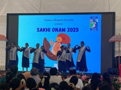  Several dancers on stage showcasing a lively performance, with vibrant costumes and dynamic movements. Sakhi Onam 