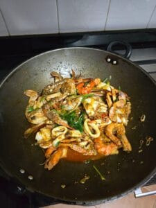 A pan sizzling with shrimp and colorful vegetables being cooked together.